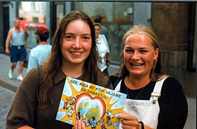 Two Estonian girls holding up a poster that says, "What Everybody Needs is Love!"
